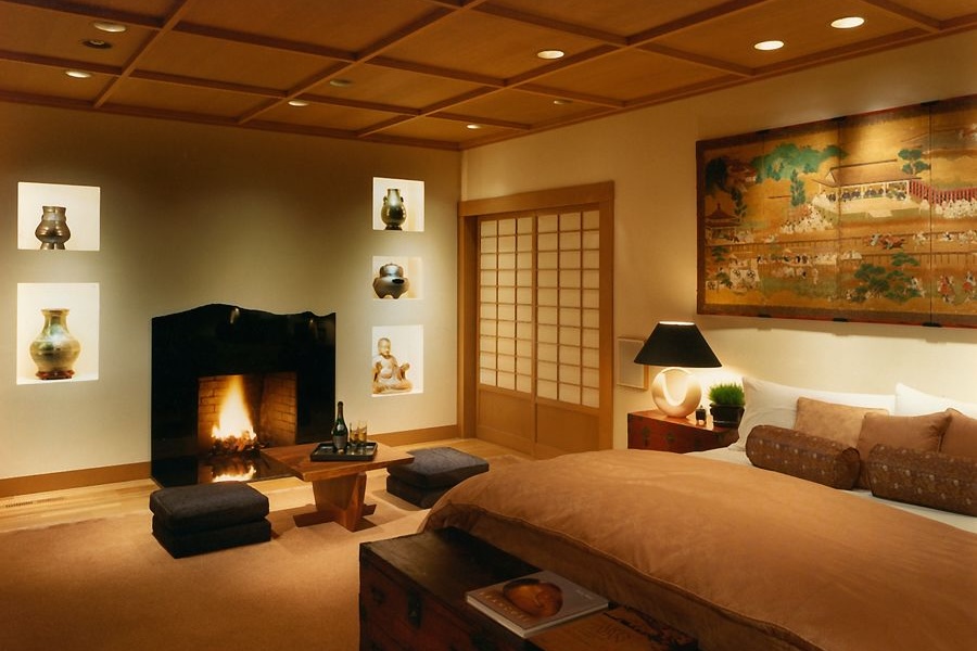 Downlights illuminate a warm, inviting bedroom space with fireplace and seating area next to bed.