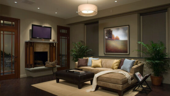 A living room with Lutron shades and lighting, in-ceiling speakers, and a TV above the fireplace.