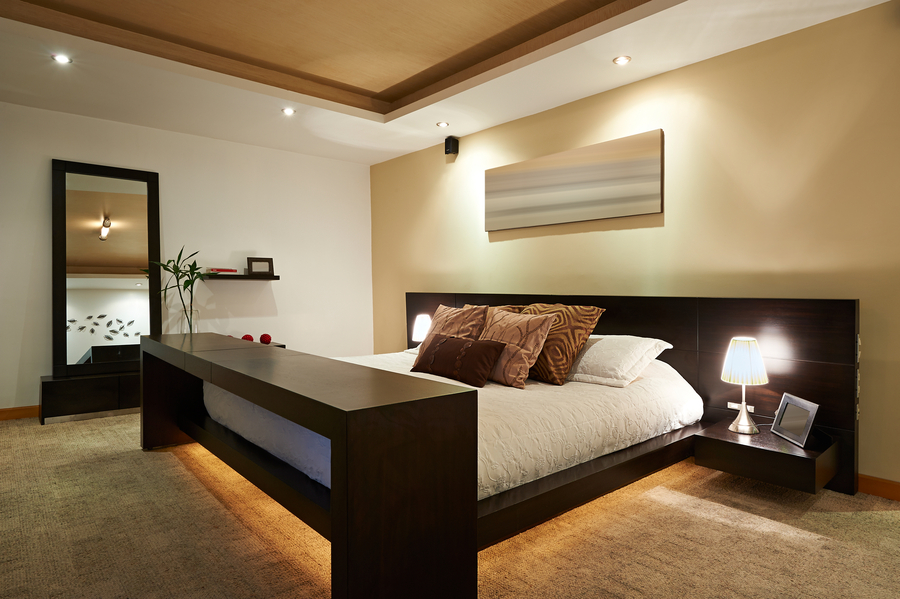 Image is of a beautiful modern bedroom with lighting under the bed as well as on the ceiling.