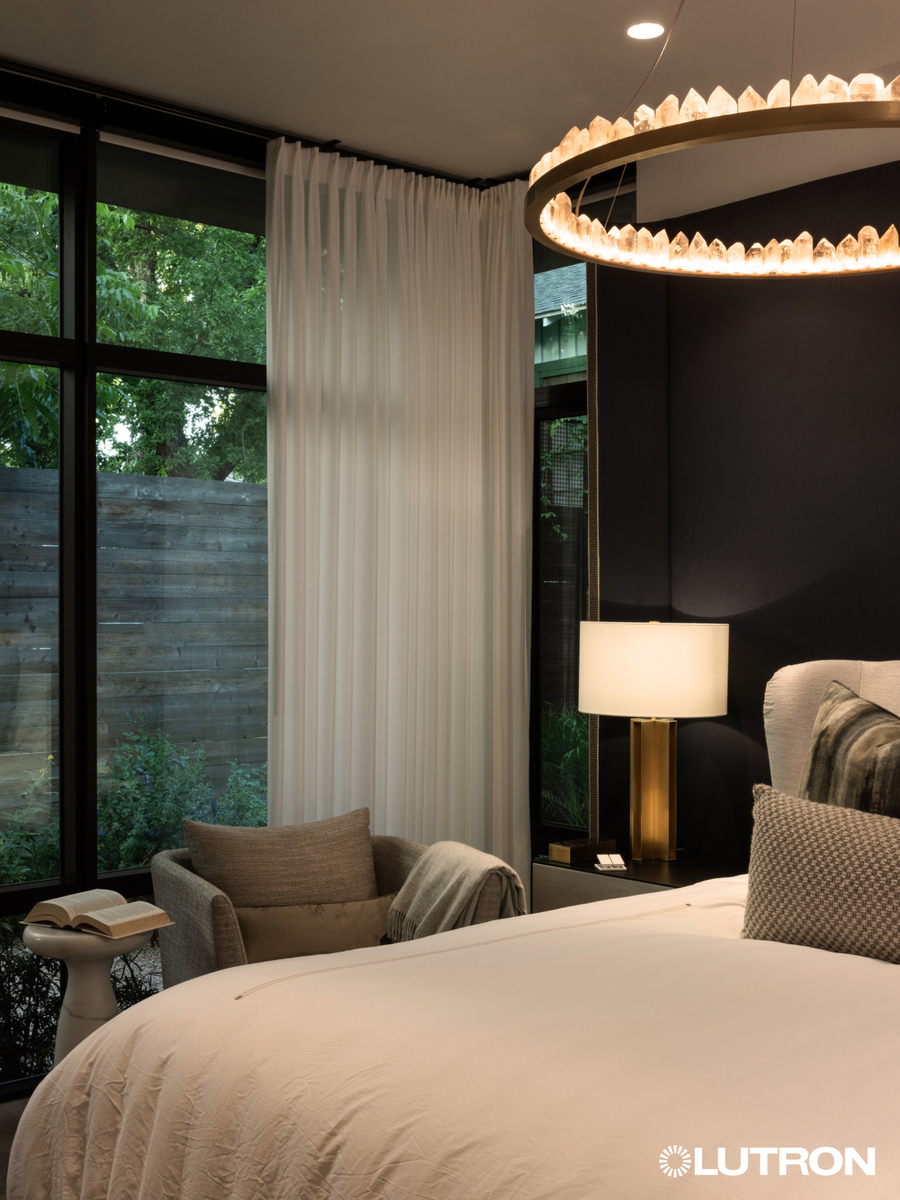 Lutron lighting and shades in a luxurious bedroom; drapes are partially opened.