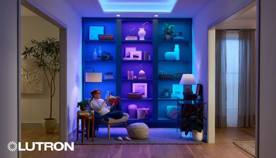 A person reading a book in front of a bookcase illuminated by Lutron Lumaris tape lighting.