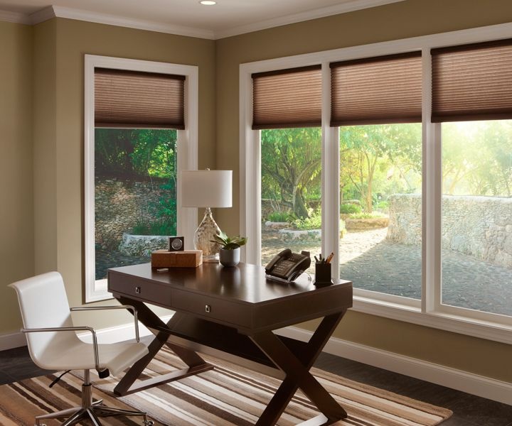 Home office with Lutron motorized shades partially drawn, filtering sunlight across large windows and sleek decor.