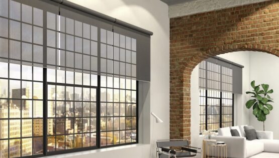Lutron Palladiom motorized shades partially lowered on large floor-to-ceiling windows in a modern brick luxury loft.