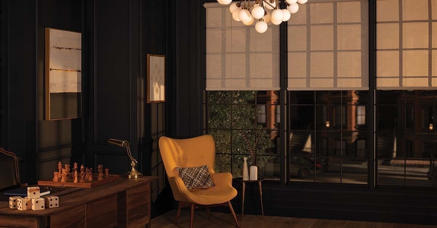 Cozy den with dark walls, motorized shades, chandelier, armchair, and a city window view.
